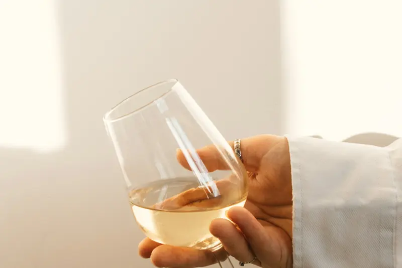 Mano sujetando una copa de vino blanco