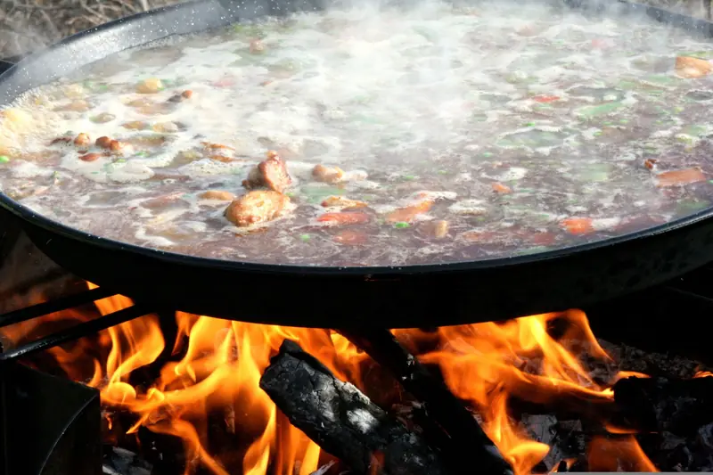 Paella valenciana cociéndose al fuego de leña