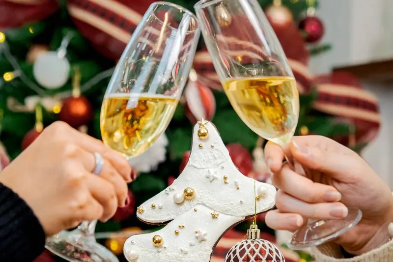 Dos personas brindan con copas de cava delante de un árbol de Navidad